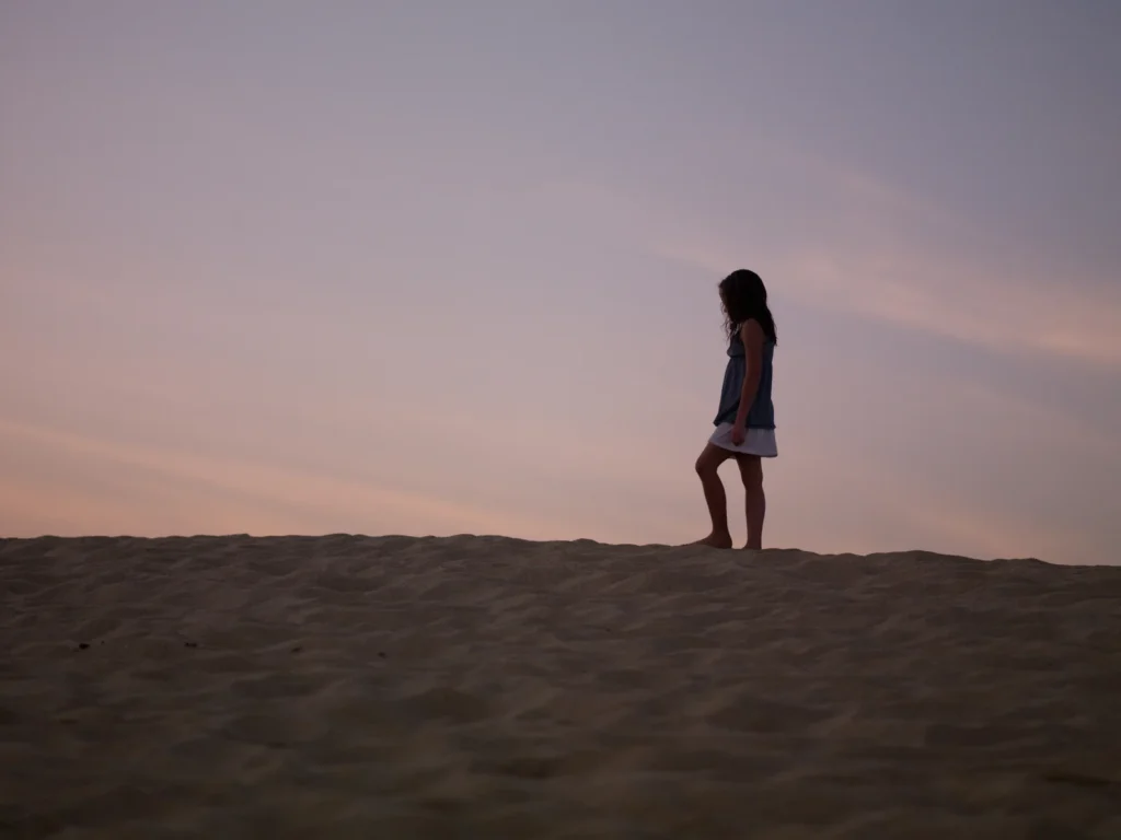 Silhouette of young girl on beach at sunset