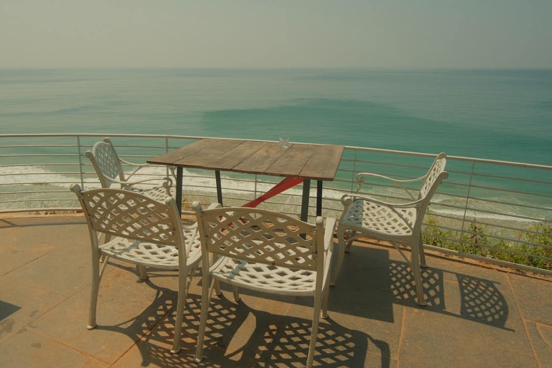 A refreshing margarita cocktail sits on a table on a sunny patio, with a beautiful blue ocean view in the background, symbolizing a successful and stress-free renovation.