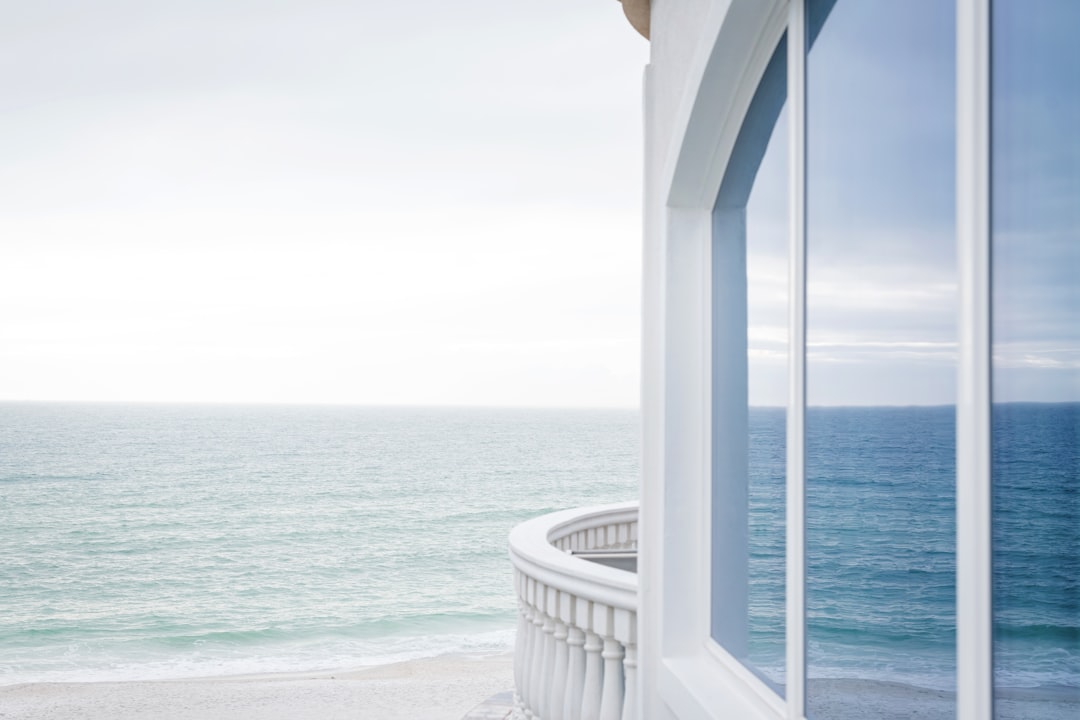 A stunning, aspirational view from a luxury villa in Cabo, featuring a modern infinity pool that overlooks the turquoise ocean under a bright, sunny sky.