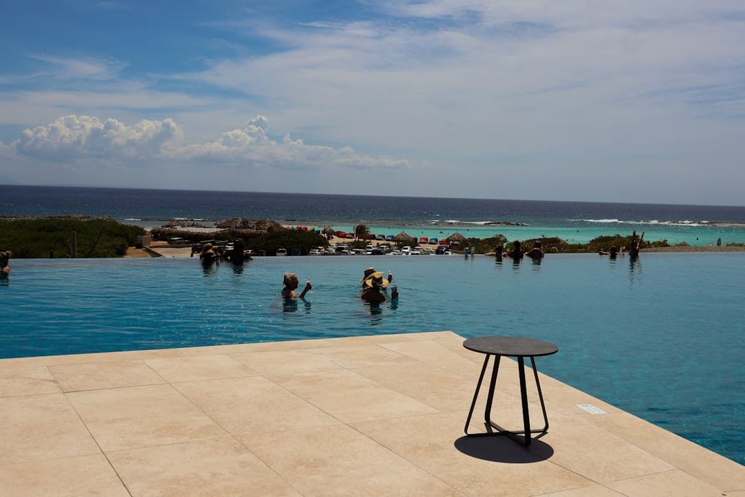 The clean, modern architecture of a luxury villa in Cabo, featuring an infinity pool that seamlessly blends into the horizon of the Pacific Ocean at sunset.