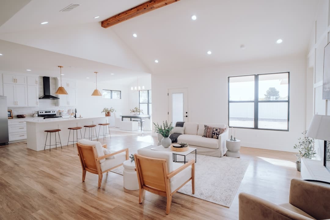 A professional real estate agent in a bright, modern living room hands house keys to a smiling person, successfully closing a home sale.