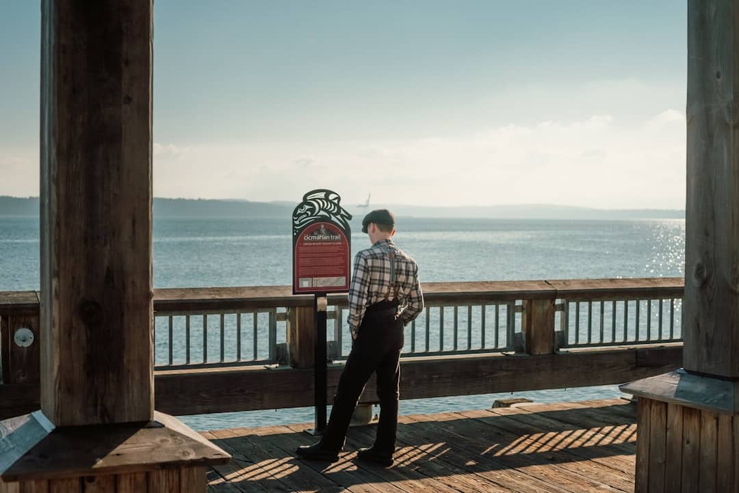 A person stands on the balcony of a modern home, thoughtfully looking out at the ocean horizon, symbolizing strategic foresight and planning an exit strategy for a real estate investment.