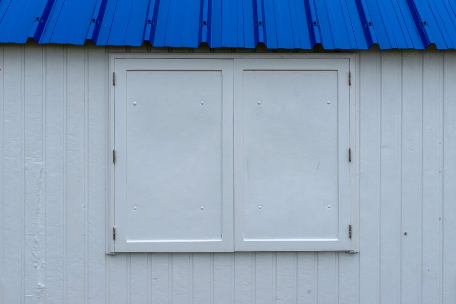 Close-up architectural detail of a modern beach house with hurricane storm shutters closed, conveying a sense of security and preparedness against bad weather.