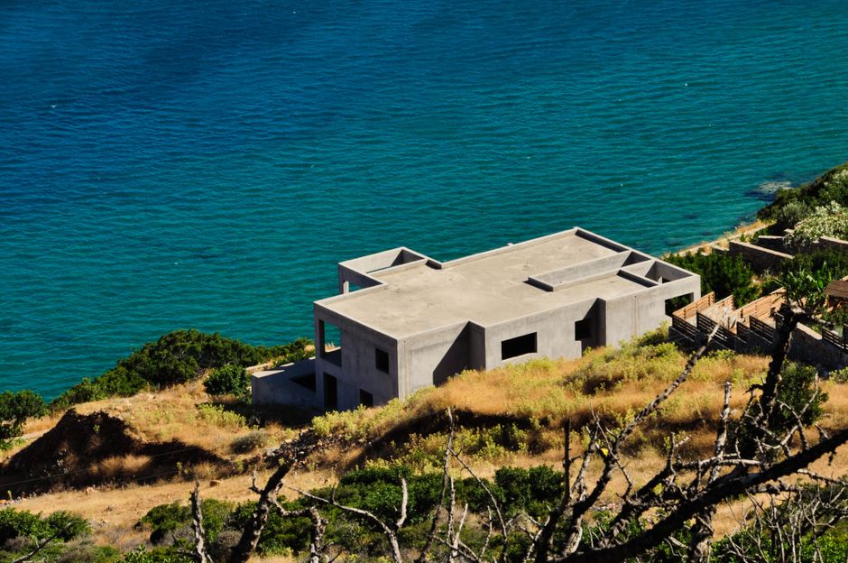 The construction site of a luxury home with a concrete and steel frame, set against a beautiful coastal backdrop, representing the building process in Cabo.