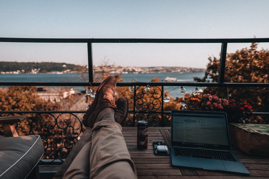 Professional working on a laptop from a lounge chair next to a luxury infinity pool overlooking the ocean in Cabo.